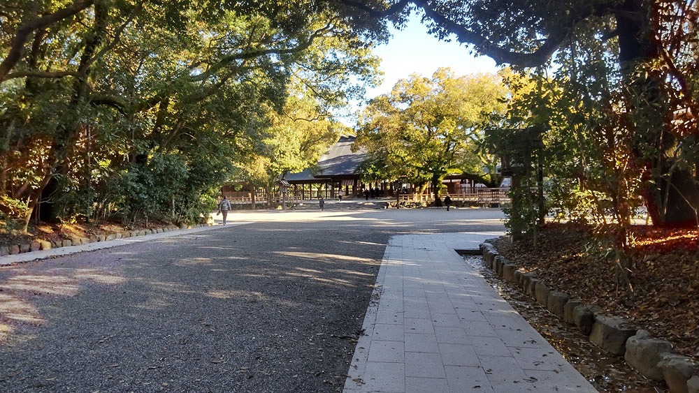 名古屋市熱田区にある熱田神宮の境内風景。大きな木々に囲まれた参道の先に拝殿が見え、静寂で厳かな雰囲気が漂う風景